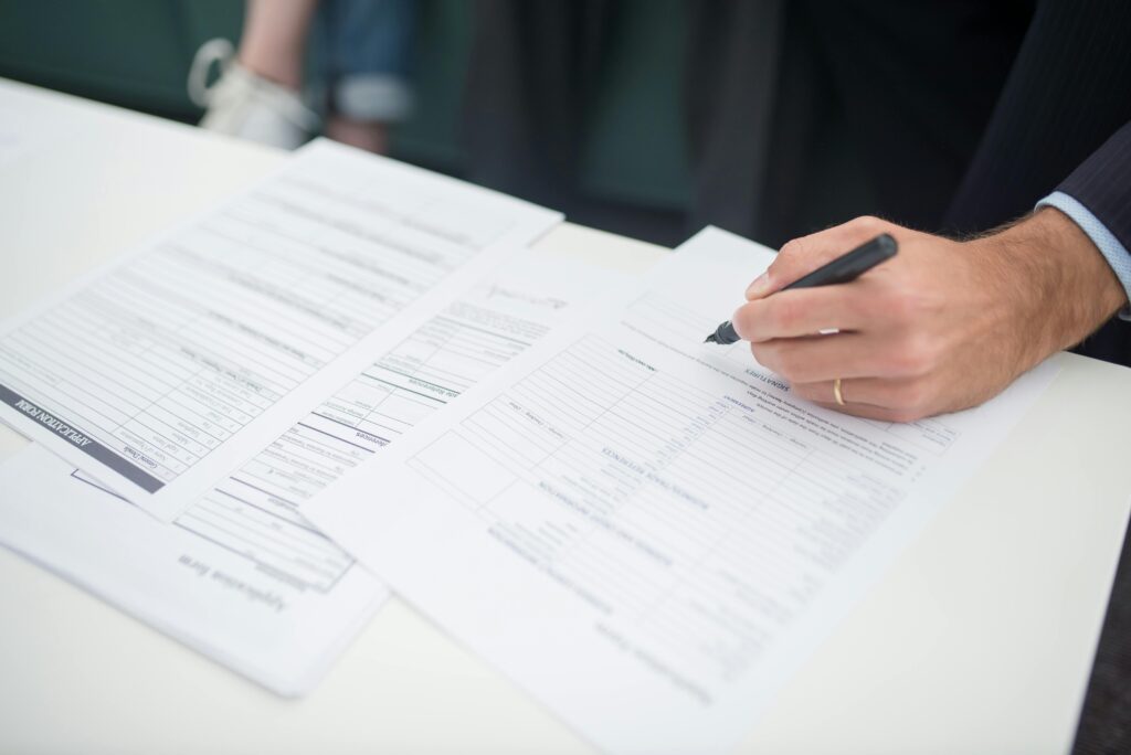 Close-up of a hand signing insurance documents in an office setting.