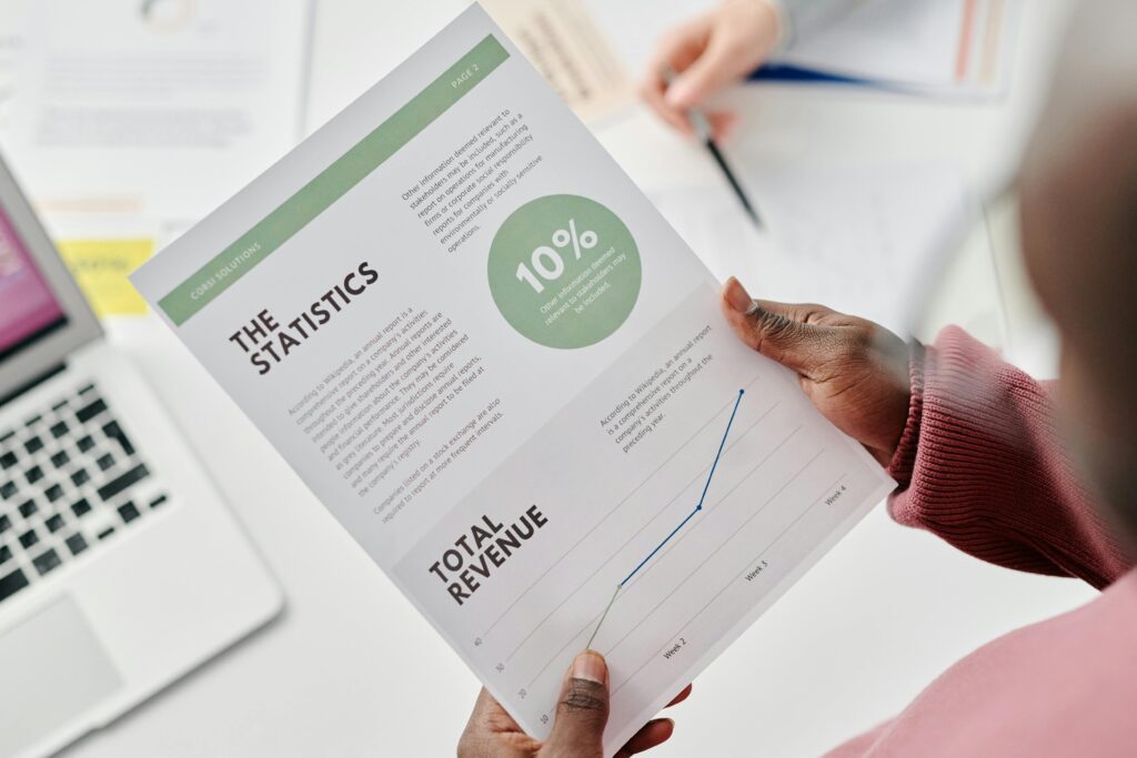 Hands holding a statistical report during a business meeting. Includes revenue graphs and analysis.