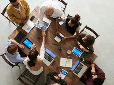 Top view of a diverse team collaborating in an office setting with laptops and tablets, promoting cooperation.